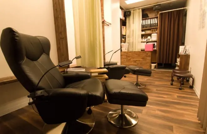 落ち着いた照明と木目調の床が特徴の、ネイルサロンの施術スペースの内観