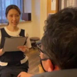 ネイリストがニッパーで丁寧に指先の甘皮処理を行っている施術中の様子