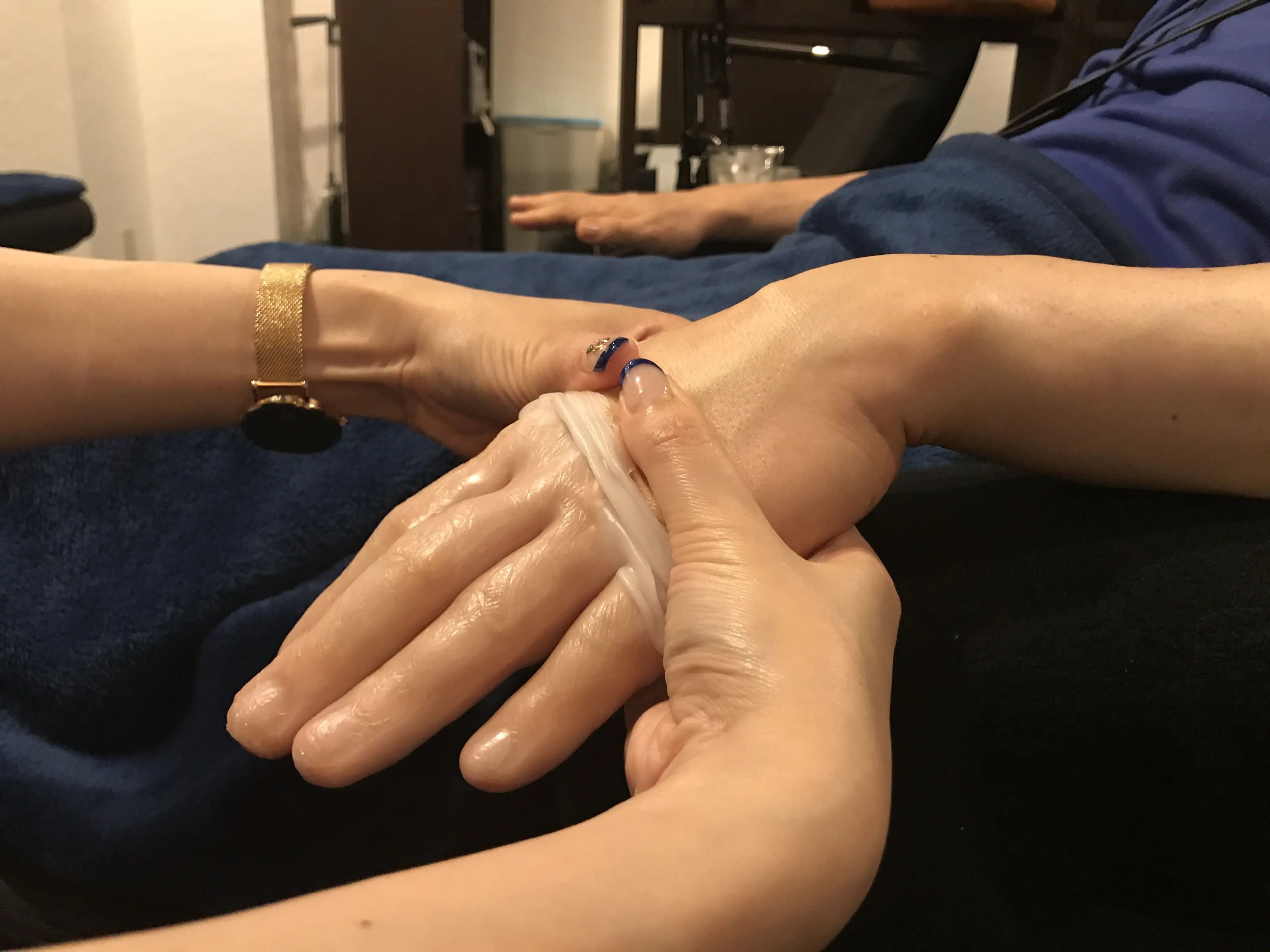 保湿剤を塗った手にラップを巻き、ハンドトリートメント中のシーンでリラクゼーションを演出